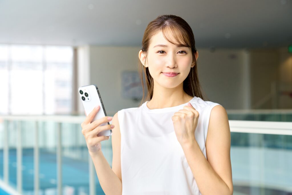スマホを持ってガッツポーズする若い女性