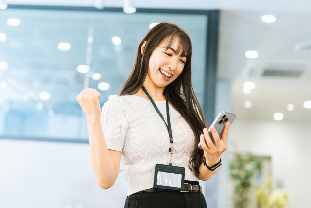 スマートフォンを見て喜ぶビジネスウーマン